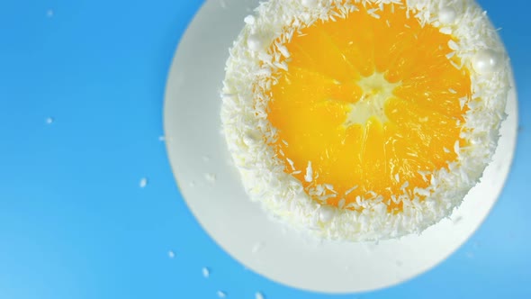 Cake with Orange and Coconut Shavings Spinning on a Blue Background alt