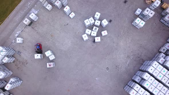 Forklift truckse between large shelves at outside warehouse and load pallets.Aerial. Drone shot alt