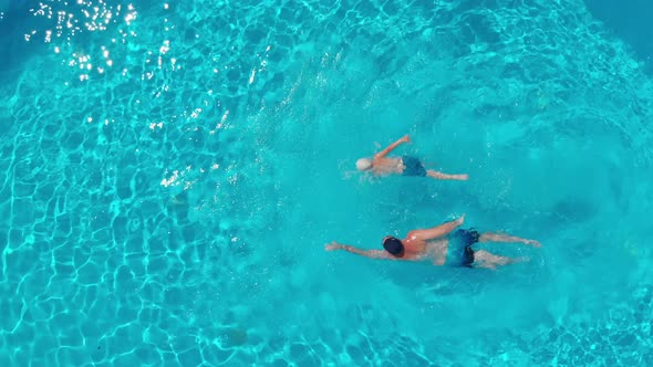 A Top View of a Man and a Boy Swimming in a Clear Open Swimming Pool