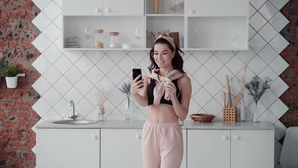 Happy Girl Standing at Home Kitchen and Holding Video Call. Young Woman Talks with Friend. Vlogger