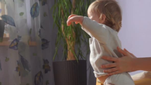 Mother Is Helping Her Baby To Take the First Steps alt