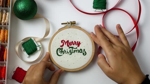 The woman embroidered the words Merry Christmas. Christmas gifts with her own hands.