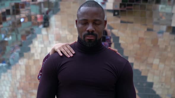 Close-up Portrait of an African-American Man, He Stands Against a Wall Consisting of Small Square alt