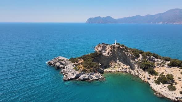 drone flight over the island on which there is a lighthouse inside the mediterranean sea against the alt