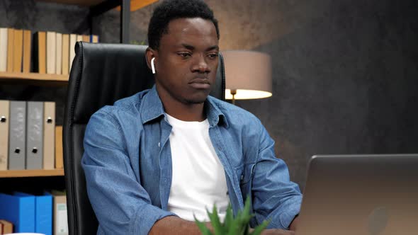 African American Man Works for Laptop in Office Writes Information in Notebook alt