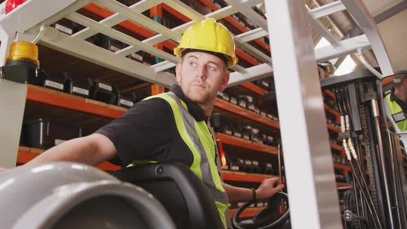 Caucasian male factory worker at a factory with a hat and high vis vest, using a truck alt