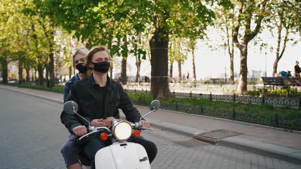 Happy Young Hipster Couple Riding a Vintage Scooter in City in Protective Masks During Pandemia of alt