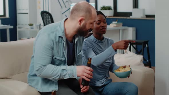 Man and African American Woman Enjoying Chips After Work alt