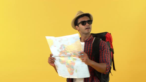 Smiling Asian male backpacker walking and looking at the map