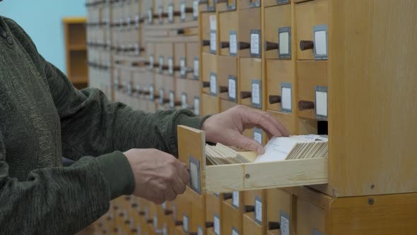 A Male Hand Searching Cards in Old Wooden Card Catalogue alt
