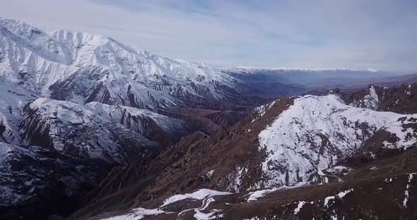landscape of mountain covered by snow in a wide view cloudy sky visible in horizon. rural road links alt