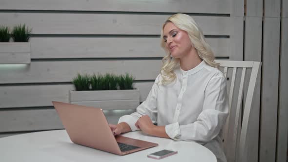 Blond Woman Freelancer Works at a Laptop at Home