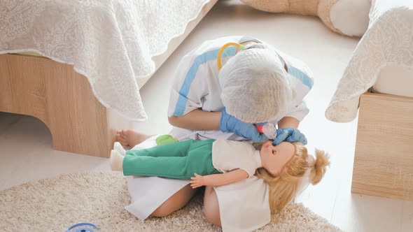 Beautiful Little Girl Playing Doctors with Doll at Home alt