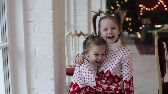 Cute Little Sisters Standing at Home and Hugging, Enjoying Christmas