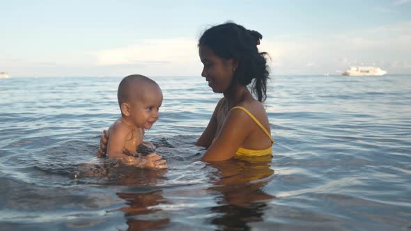 Mother and Adorable Little Baby Enjoys Bathing in the Sea on Summer Afternoon