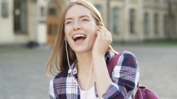 Attractive Young Woman Walking at The Street, Listening to Music