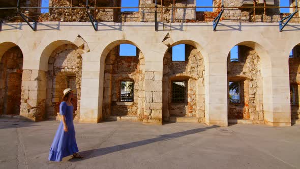 A young girl in a blue dress at the old building alt