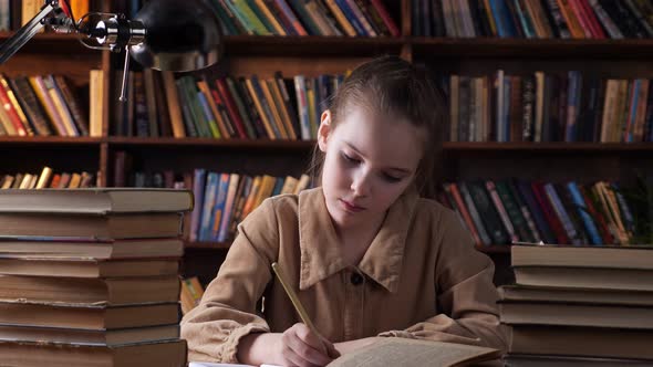 Bored Schoolgirl Looks Into Book and Writes in Copybook alt