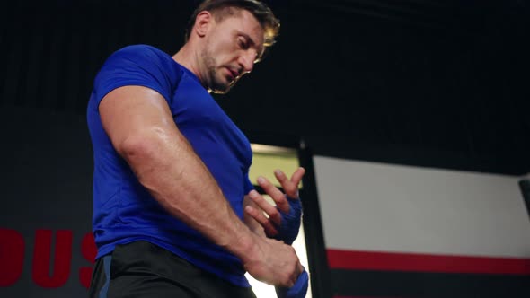 4K Caucasian man wrapping hands with boxing wraps while do boxing exercise at gym. alt