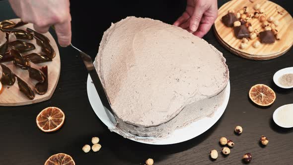 Woman baker is making cream chocolate cake, hands close up. alt