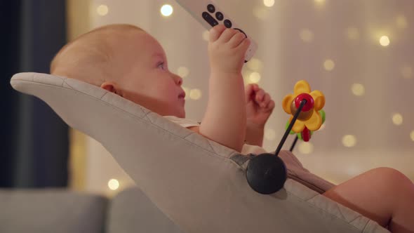 Child Watching TV in Living Room Cute Baby Boy Holding Tv Remote Sitting in Rocking Chair alt