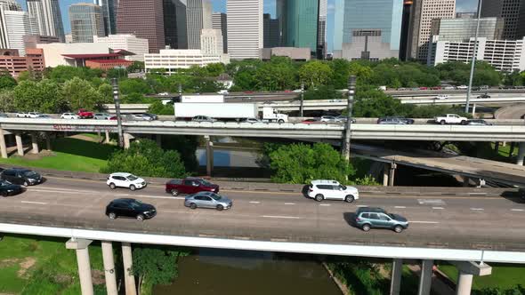 Aerial reveal of downtown Houston Texas skyline as traffic rushes by on interstate freeway highways. alt