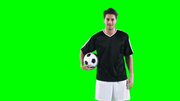 Football player holding a football against green screen alt