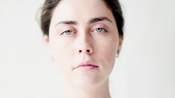 Close-up portrait of a young Caucasian sad woman on a white background alt