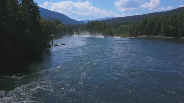 Aerial Drone Traveling Above Flowing Water On Lake With Mountains And Evergreen Trees 1