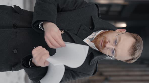 Vertical Video of the Businessman Reading Some Documents Looking Serious alt