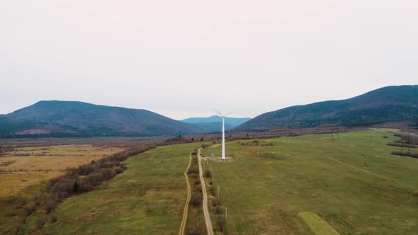 Lonely windmill in the field between Carpathian mountains of Ukraine in spring against a background