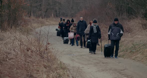 War Immigrants With Luggage Walking On Road During Snowfall alt