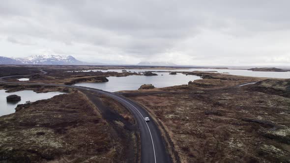 Aerial tracking view of a car driving near Lake Myvatn on gorgeous landscape in Iceland alt