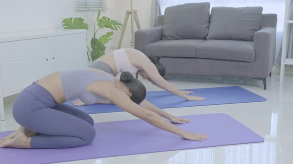 Asian people practicing yoga lifestyle class on a mat at living room