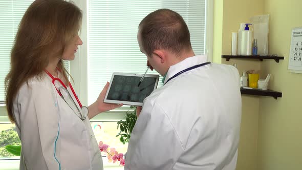 Male and Female Doctors Analyze Head Mrt Photos in Tablet Computer