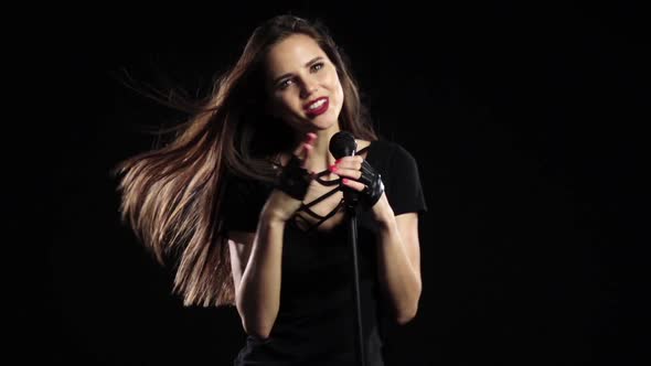 Girl Dances and Sings at a Rock Concert, Her Body Is Sexy. Black Background. Slow Motion alt