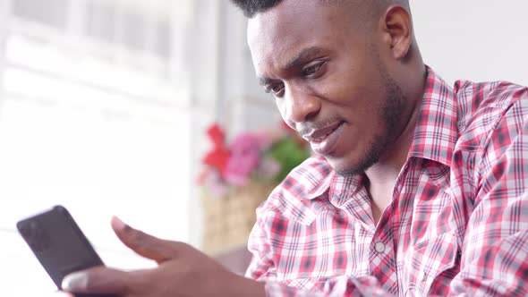 Close up hands African man sitting on sofa, holding smartphone and searching alt