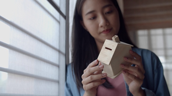 Attractive portrait young Asian woman freelance architect holding a model of home.