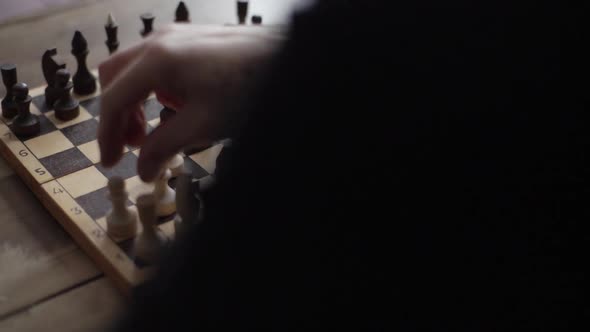 Closeup View From Back of Unrecognizable Chess Player Performing Move with Pawn Piece on Wooden alt