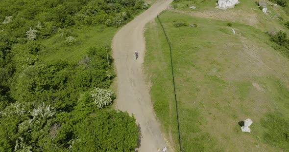 Motorcycle emerging from the forest and driving on an off-road trail in Kojori. alt