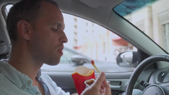 French Fries in Paper Packaging. Hands of Men Holding French Fries in the Car. Snack, Junk Food alt