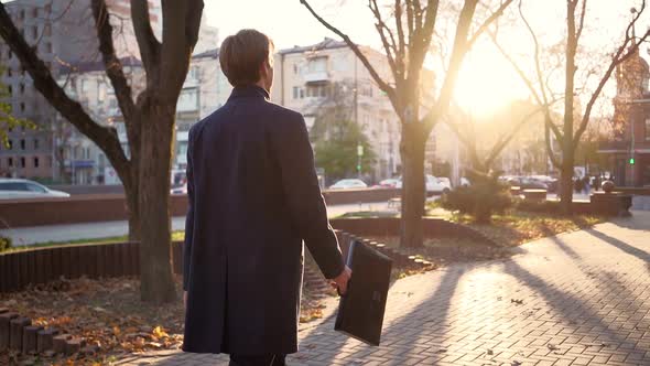 Serious Handsome Business Man Walks After Work in the Sunset Light of the City. alt