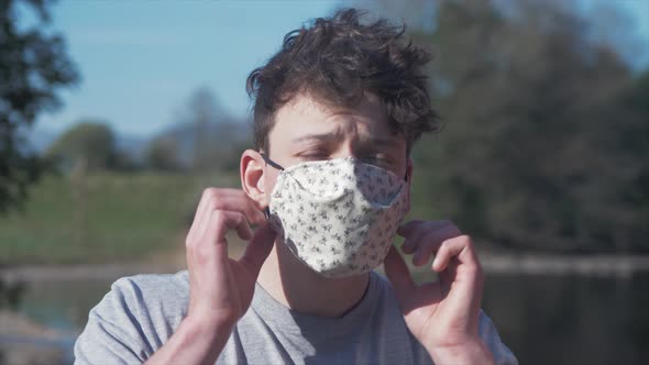 Young man puts on homemade white cotton corona virus mask MID SHOT alt