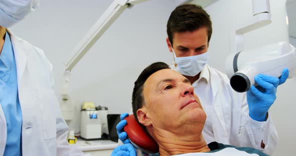 Dentist examining a male patient with dental tool alt