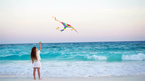 Little Girl with Flying Kite on Tropical Beach at Sunset. Kid Play on Ocean Shore. Child with Beach