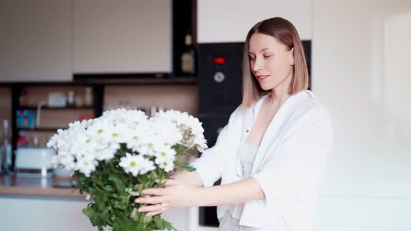 Beautiful Woman Putting Fresh White Flowers Into a Vase