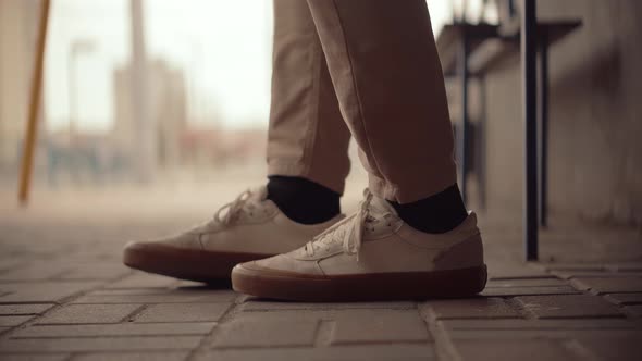 Travel Man Sitting On Bench Tram Station And Moving Legs. Businessman Nervous Stomping Legs. alt