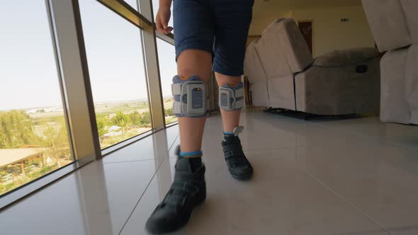 Boy with foot drop system walking indoor alt