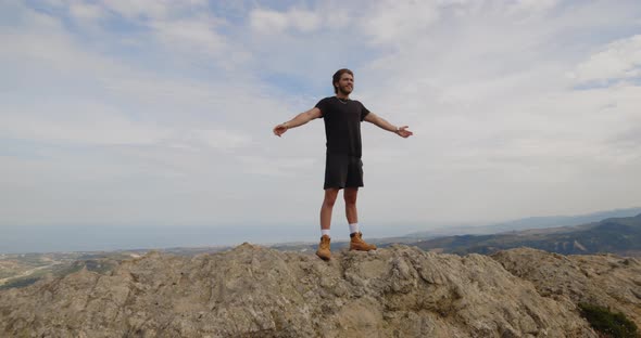 Boy spreads his arms and enjoys life on the top of a mountain alt