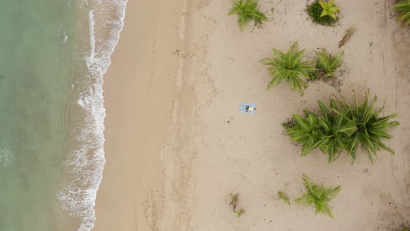Drone view of a man lying on the beach alt